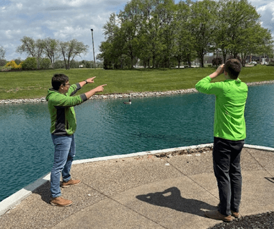 Choice One Engineering staff near the office pond with geese swimming in the water.