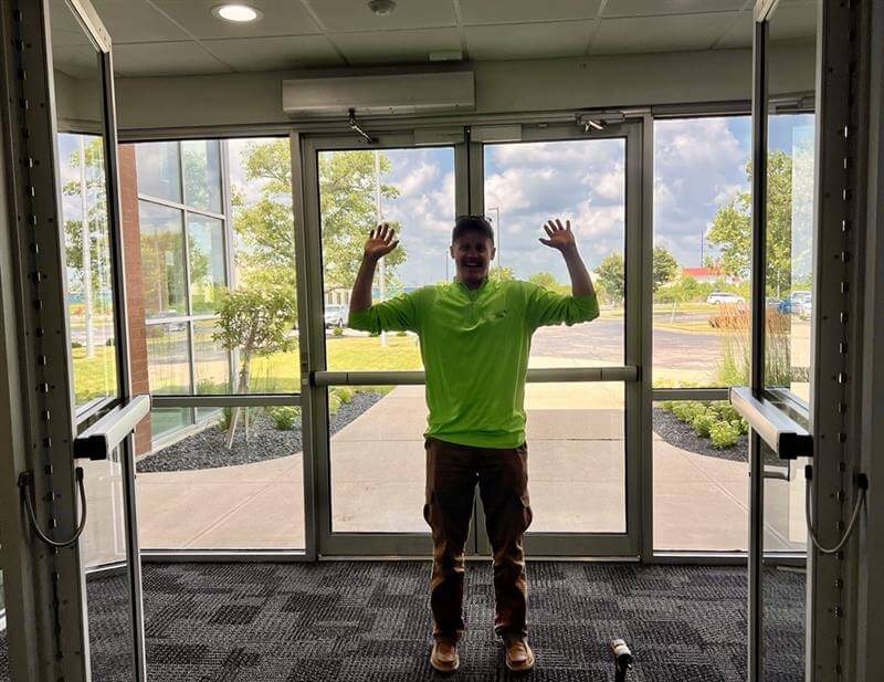 A Choice One surveyor poses with hands up by open doors.